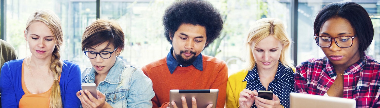 A diverse group of five people sitting and using smartphones and tablets.